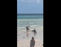 Couple back-to-back carries each other on beach