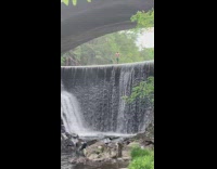 Man green shorts jumps on the large waterfall