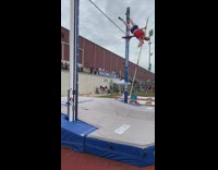 Guy pole vaults, lands on top of green bar and snaps it in half