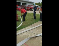 Water shoots out of firefighter hose on both sides during training at firehouse 