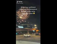 Girl filming fireworks while guy fills car with gas 