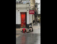 Guy fishes out a mug from hole in sidewalk