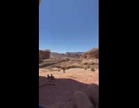 Lady in pink outfit stands on rock under arch 