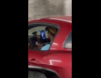 Man drive red car play cowbell instrument