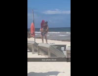 Pink hair woman red thong is held by boyfriend beach