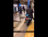 Guy rides scooter off subway train onto the platform