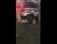 Two girls kneel on man hole for coffee cup