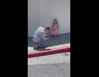 Woman pink dress and heels crouch wall sidewalk