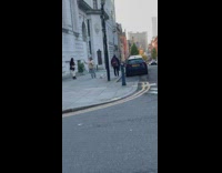 Woman in black coat poses at the sidewalk