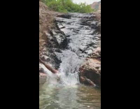 Slo-mo video guy slides down small waterfall
