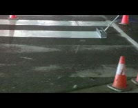 Men repaint pedestrian white lines on ground 