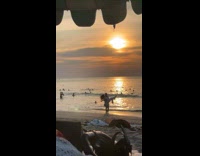 Couple run towards beach with camera behind