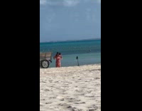 Woman red dress dances at the beach