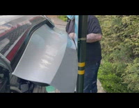 Car trunk door very close to signage pole