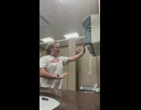 Girl in bathroom pretends to control paper dispenser 