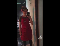 Girl in front of mirror in red starbucks apron 
