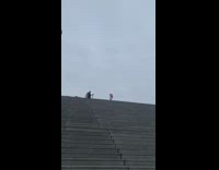 Man pink coat arm gestures over stairs