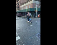 Guy rides blue bicycle while holding crutches 