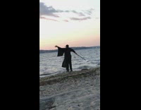 Guy black robe stick martial arts beach