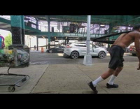 Man ties rope to chest and pulls several shopping cart full of plastic recyclable bottles down the sidewalk