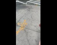 Man sleeps inside shopping cart next to trash can on sidewalk