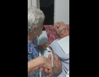 Elderly Man Holds Elderly Wifes Hand and Kisses it