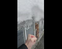 Guy punches icicles hanging on rooftop edge 