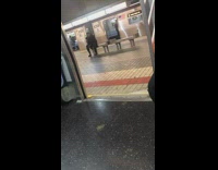 Man on bench smokes cigarette in subway station, open car doors