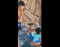 Little boy in jacuzzi throwing up hand signs and middle finger