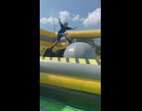 Boy blue shirt shorts jumps on big gray balls on inflatable obstacle course and bounces off