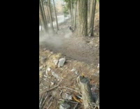 Mountain biker rides off wooden platform, rides fast down trail and falls down at the bottom