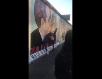 Couple vertical leg split beside kiss mural