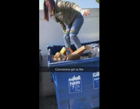Lady steps on boxes in blue dumpster 