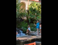 Woman in dress sits beside small waterfalls