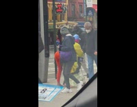 Woman orange pants push scooter on street
