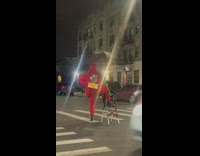 Guy in red outfit holding a umbrella standing on step ladder at night