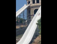 Man shirtless slides down and splashes in the pool