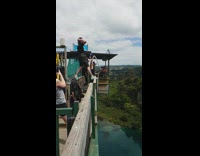 slomo of a man bungee jumping over green lake