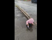 Young girl stomp and sit on water puddle