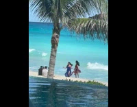 Two women in blue and red dress dance at the beach