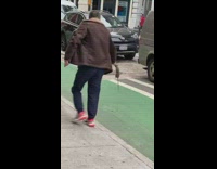 Man holds dead rat with tongs and rushes down the street