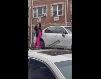 Woman using hammer to destroy vehicle on back of tow truck