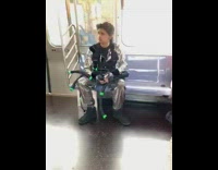 Guy wears shiny silver outfit with vest and tubes on metro train