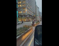 Woman sits on road barrier while she records 