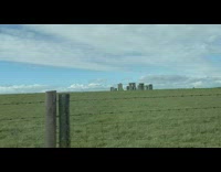 People in car drive by stonehenge grass field