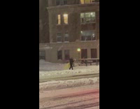Guy carries yellow surfboard through blizzard 