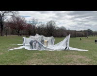 Group dance under white fabric at field