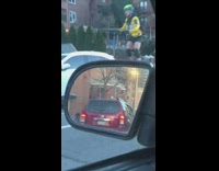 Guy wearing green helmet rides unicycle street