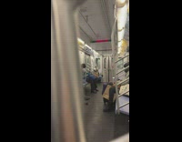 Guy sitting down on subway train balancing water bottle on head