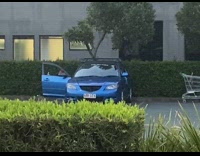 Guy film selfie video outside blue car